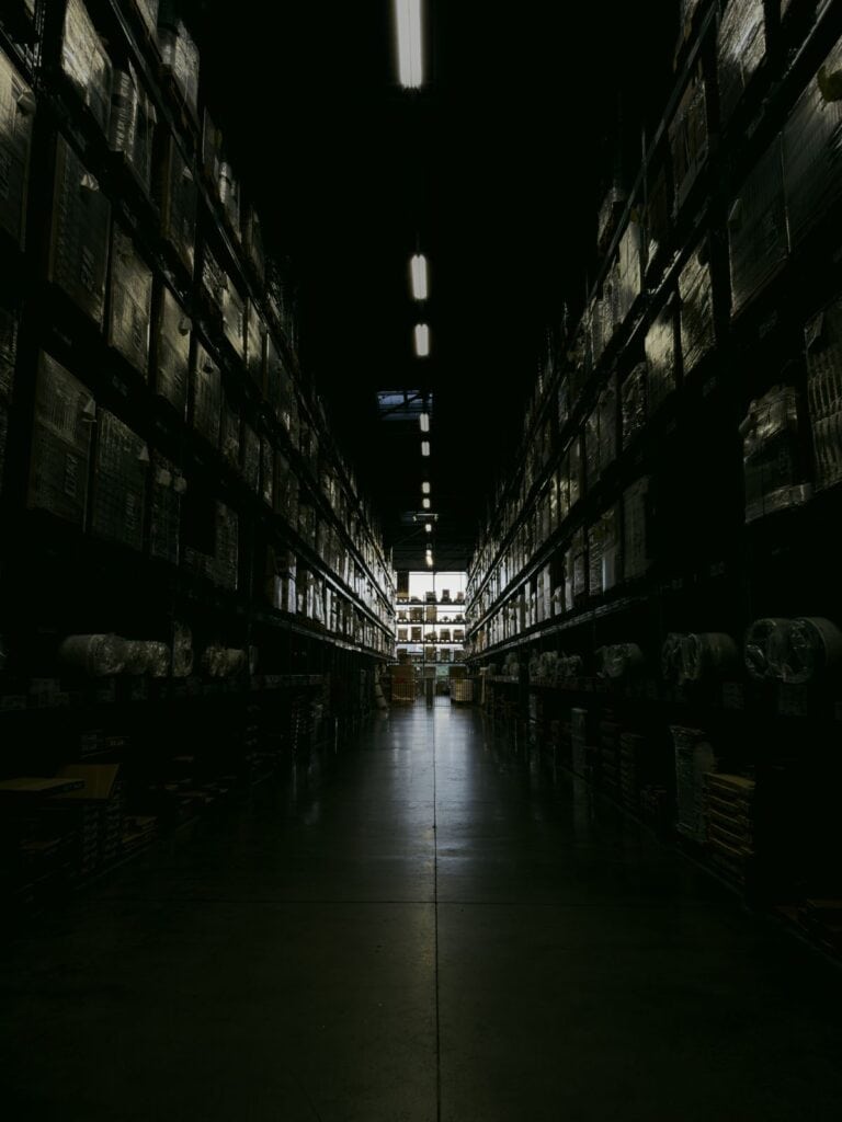 Warehouse leadership hiring delays leave an operation understaffed, shown by a quiet warehouse aisle
